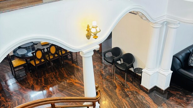 A grand staircase with a wooden railing, a white marble floor, and a dining area with tables and chairs. - Spacious, fully air-conditioned 4-bedroom ensuite home (Perumbavoor)