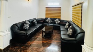 A room with a black leather sofa set, a wooden coffee table, and a ceiling fan. - Spacious, fully air-conditioned 4-bedroom ensuite home (Perumbavoor)