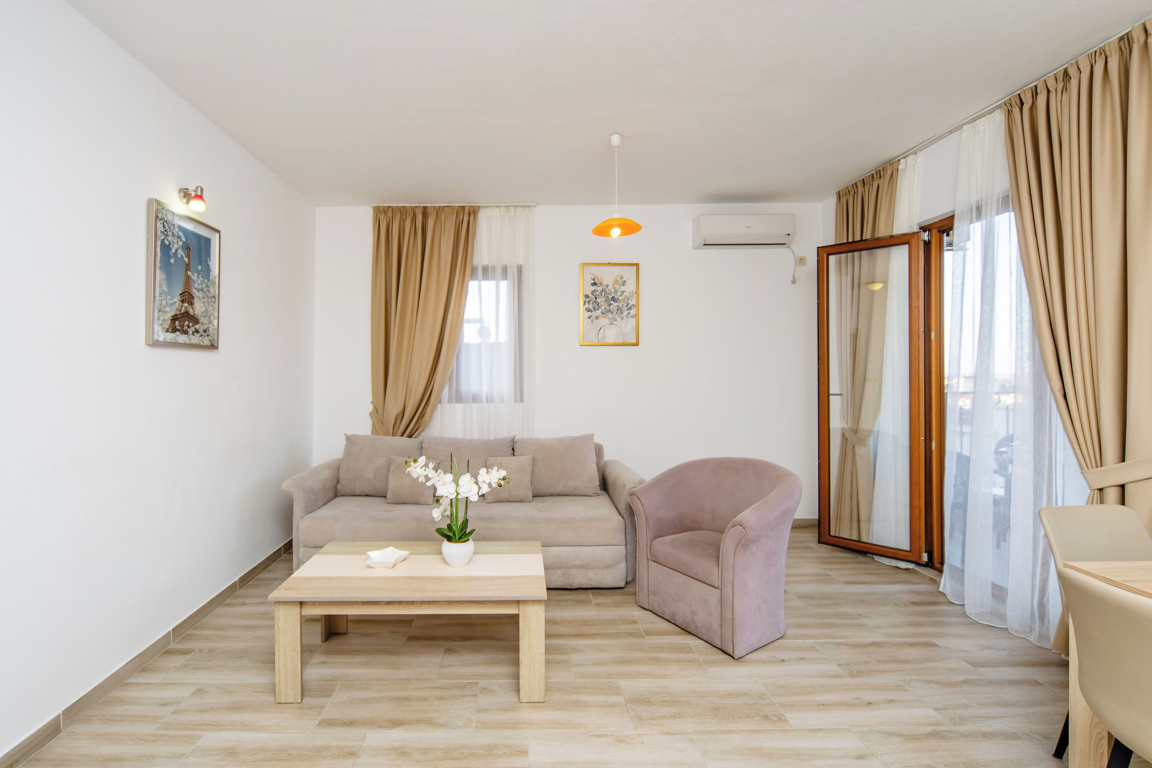 A living room with a sofa, armchair, coffee table, and artwork on the walls.