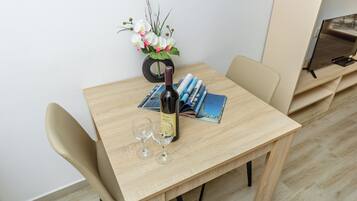 A wooden table with a bottle of wine, two glasses, and a vase of flowers.