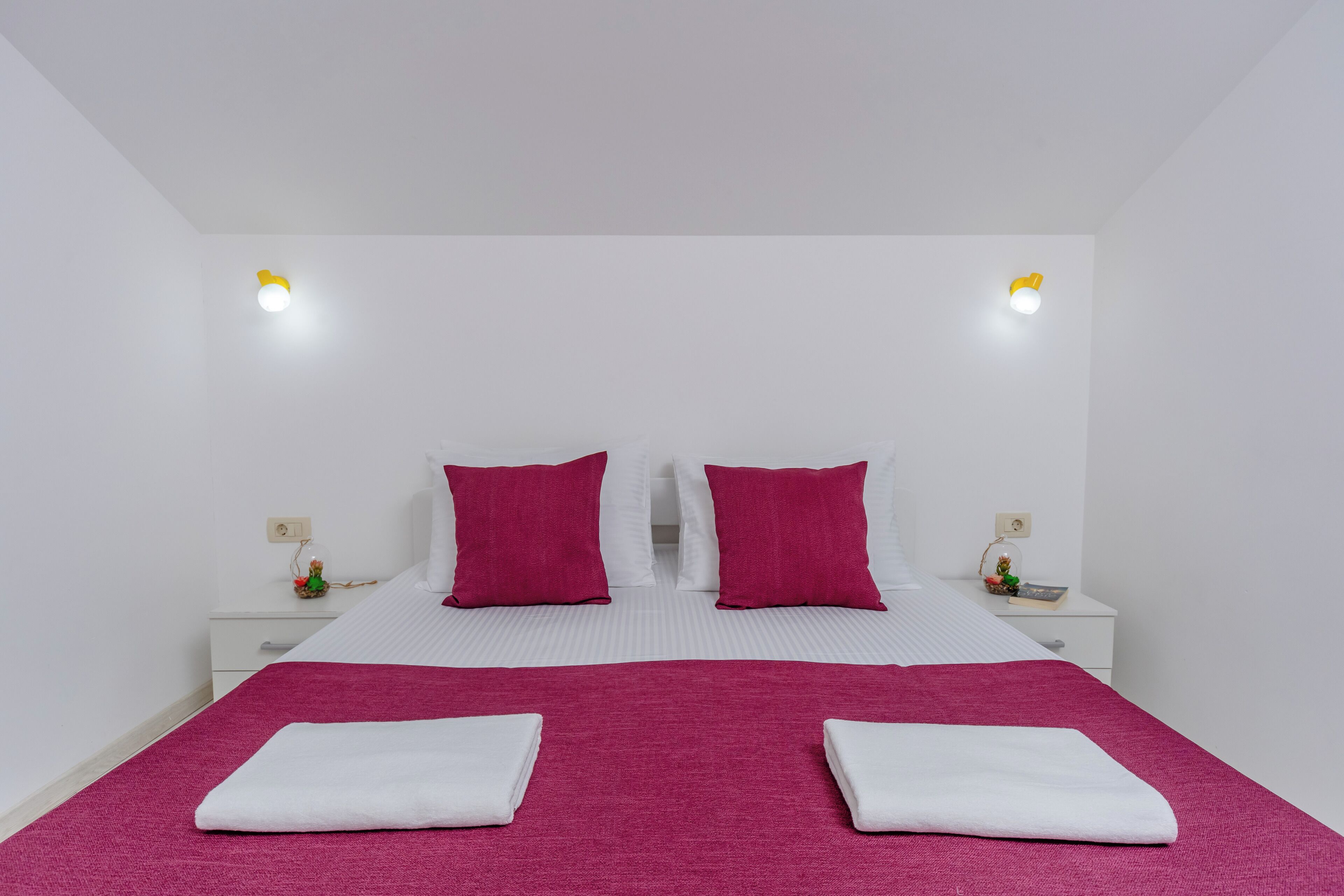 A hotel room with a bed, two nightstands, and two wall-mounted lights.