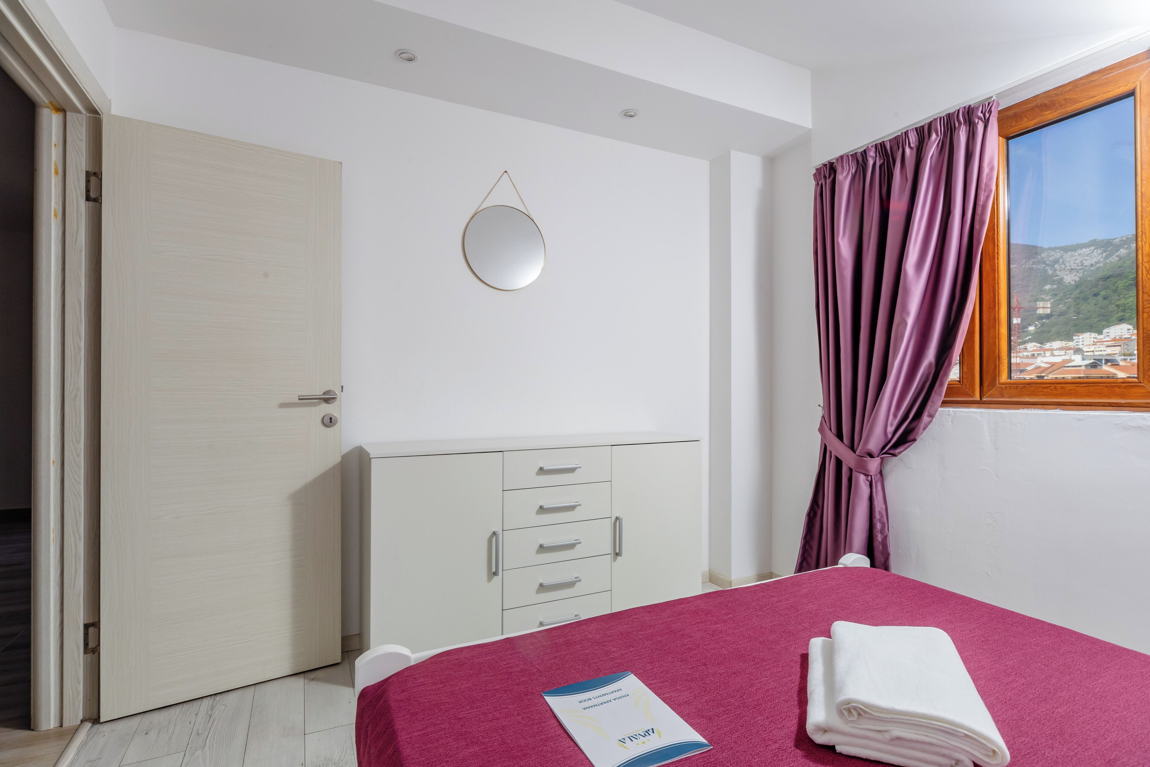 Una camera da letto con un letto, un armadio, uno specchio e una finestra con tende.