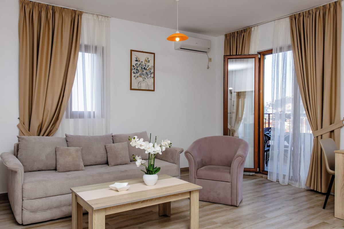 Una sala de estar con sofá, sillón, mesa de centro y un florero.