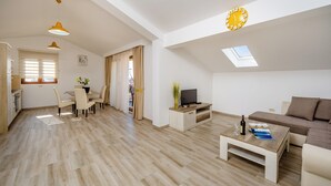 Un amplio espacio de sala con mesa de comedor, sofá, televisor y tragaluz.