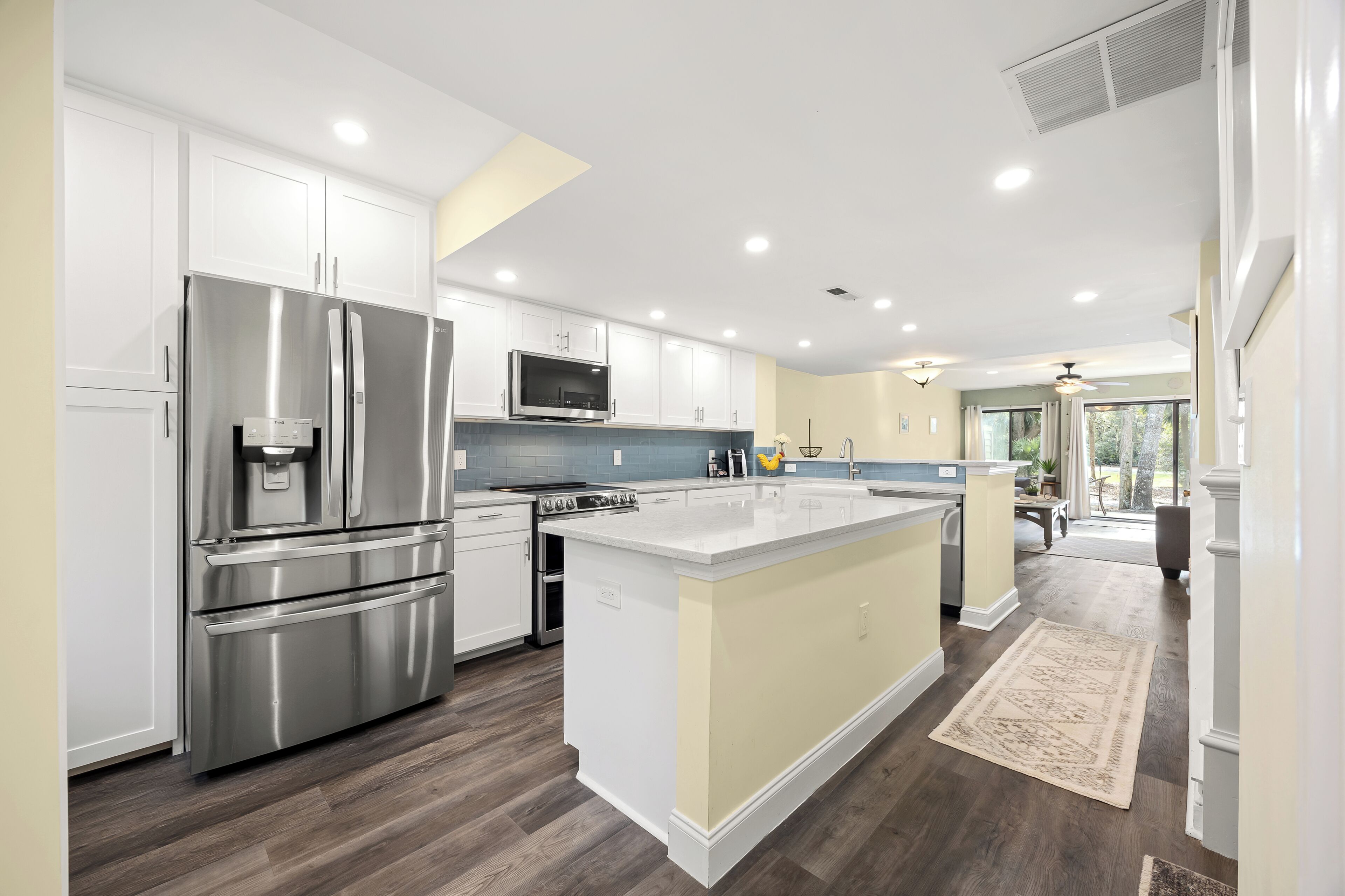 A modern kitchen with stainless steel appliances, white cabinetry, and a large island.