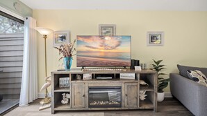 Ein Wohnzimmer mit Kamin, einer Couch, einem Couchtisch und einem Gemälde vom Sonnenuntergang.
