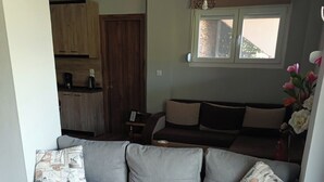 Een woonkamer met een grijze bank, een houten salontafel en een kleurrijke deken.