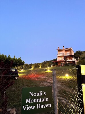 Ein Schild mit der Aufschrift 'Nouli's Mountain View Haven', im Hintergrund ein Haus.