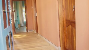 A hallway with wooden flooring, a blue door with a metal grille, and a wooden door with a handle. - Cosey Farm House and tent near  Ngorongoro, Serengeti and Manyara destinations. (Karatu - Arusha)
