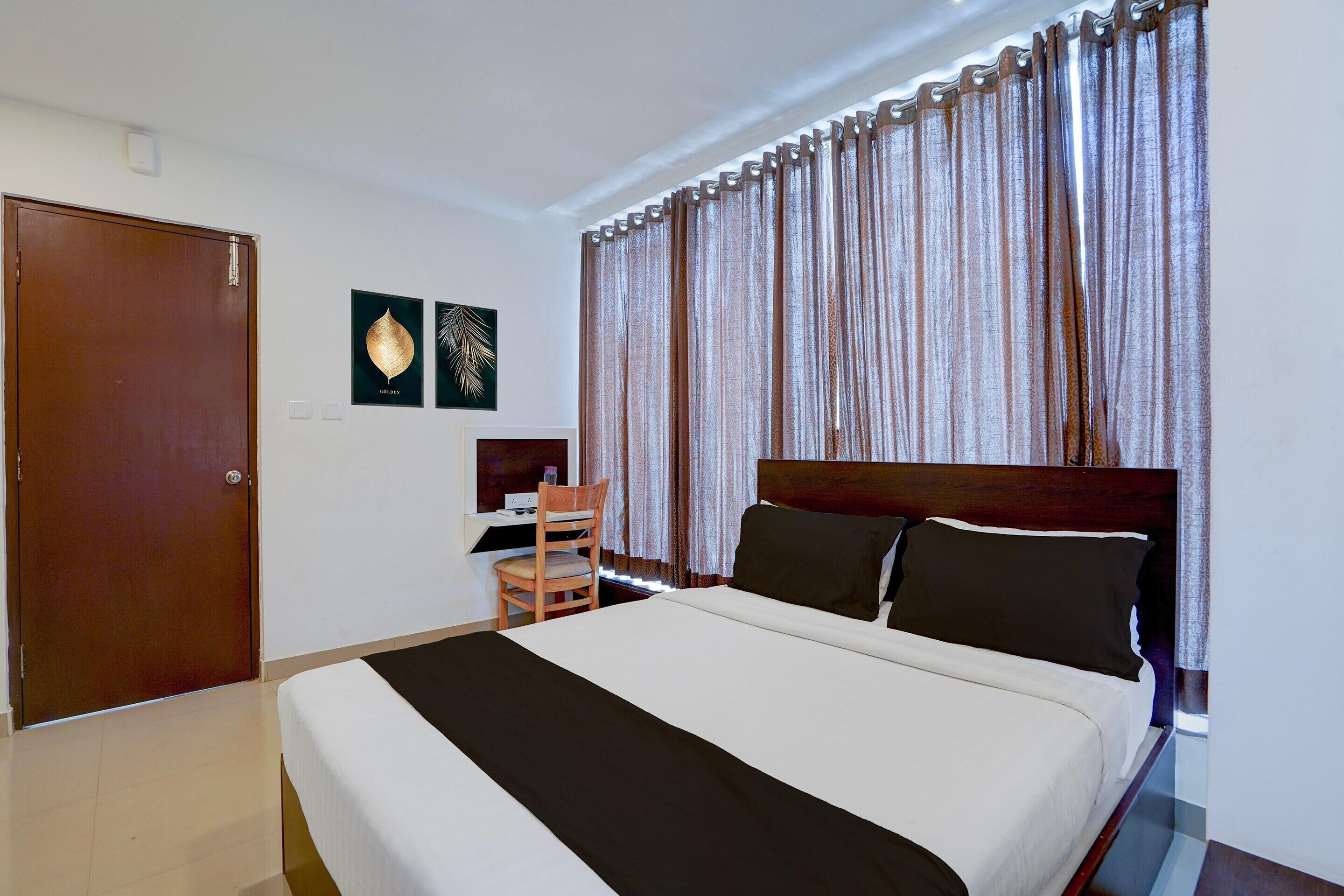 A hotel room with a bed, a desk, a chair, and curtains.