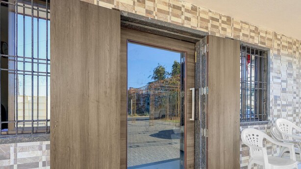 Eine Holztür mit Glasfenster, eine Kachelwand und ein Fenster mit Metallgitter.