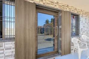A wooden door with a glass panel, a tiled wall, and a window with metal bars.