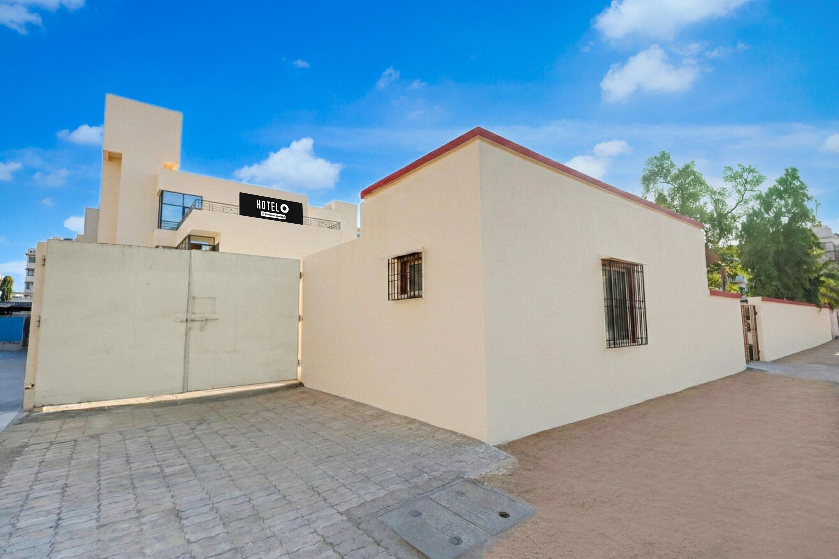 A hotel with a gated entrance, a signboard, and a paved driveway.
