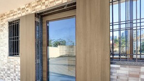 Ein Gebäude mit einer großen Glastür, einem Fenster mit Metallgitter und einer Kachelwand.