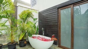 A spa area with a large bathtub filled with water and rose petals, surrounded by potted plants. - ELIVAAS Casa Del Mar 4BHK Villa & Pool (Anjuna)