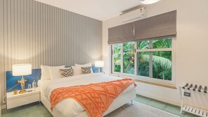 A bedroom with a bed, nightstands, a window with a view, a ceiling fan, and an air conditioning unit. - ELIVAAS Casa Del Mar 4BHK Villa & Pool (Anjuna)