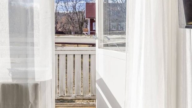A room with a view through a window, a wooden deck, and a white railing.