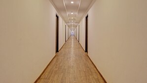 En lång, smal hall med trägolv och vita väggar, som leder fram till en dörr i slutet.