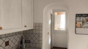 Una cocina con armarios blancos, un salpicadero de azulejos y un calendario en la pared.