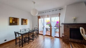 Un comedor con una mesa y sillas de vidrio, una chimenea y vistas al exterior.