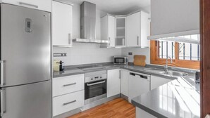 Una cocina moderna con electrodomésticos de acero inoxidable, armarios blancos y piso de madera.