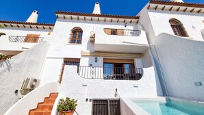 Un edificio blanco con piscina, una escalera y un balcón.