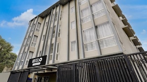 A modern hotel building with a sign indicating it is a company-serviced hotel. - Deluxehotel Gurudev Residency (Bengaluru)