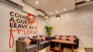 A modern lobby with a sofa set, a wooden coffee table, and a wall with a motivational quote. - Deluxehotel Palm Tree (Bengaluru)