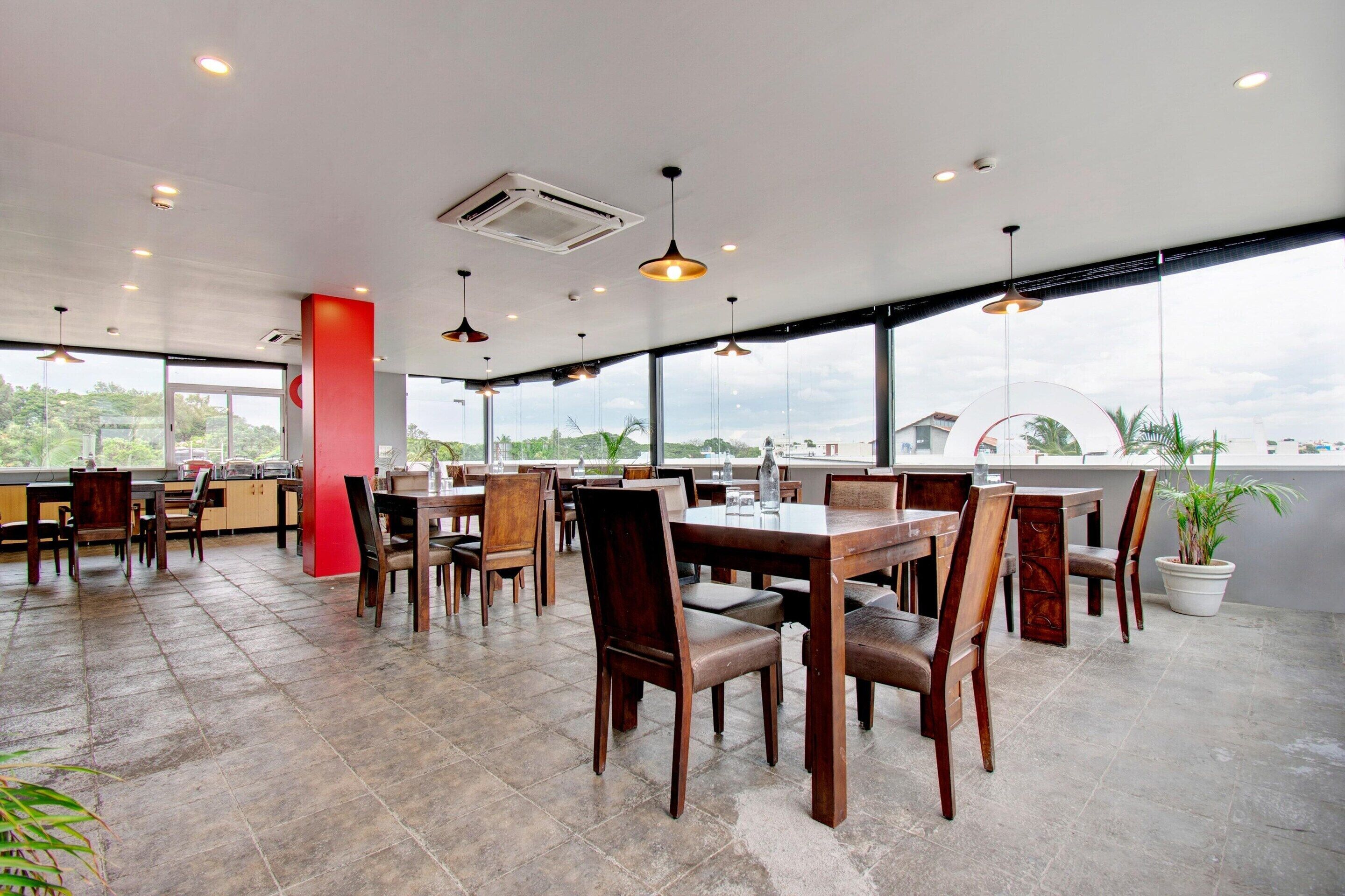 Un restaurant spacieux avec de hauts plafonds, de grandes fenêtres et une vue sur l’extérieur.