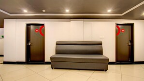 A lobby with two doors marked 201 and 202, a grey sofa, and a tiled floor. - Deluxehotel Palm Tree (Bengaluru)