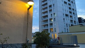 Een hoog gebouw met meerdere balkons, een lantaarn en een bord met het adres.