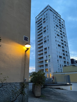 Ein hohes Gebäude mit mehreren Balkonen, einer Straßenlaterne und einem Schild mit der Hausnummer.