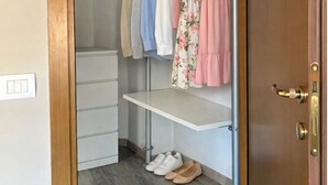 Een inloopkast met hangende kleding, een plank en een schoenenrek.