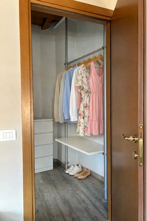 Ein begehbarer Kleiderschrank mit Kleiderstange, Ablagefläche und Schuhregal.