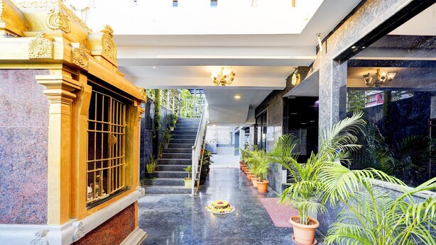 Un hall d’hôtel avec un sol en marbre, un escalier et des plantes en pot.