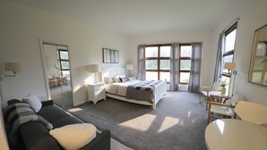 Een slaapkamer met een bed, een bank, een tafel en een spiegel.