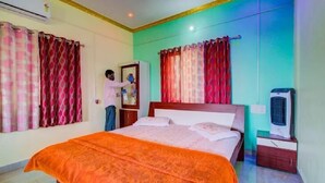Une chambre à coucher avec un lit, des rideaux, un climatiseur, un radiateur et une table de chevet.