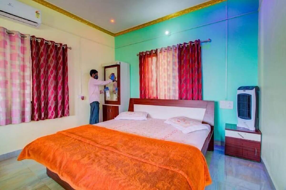 A bedroom with a bed, curtains, an air conditioner, a heater, and a nightstand.