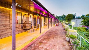 A covered outdoor area with wooden walls, hanging chairs, and potted plants. - Mayur Agro Park Resort (Bhilar)
