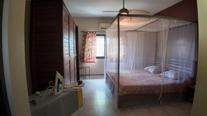 Une chambre à coucher avec un lit à baldaquin, un ventilateur de plafond et une fenêtre avec des rideaux.