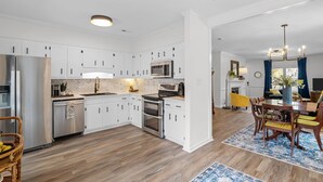 Eine moderne Küche mit weißen Schränken, Edelstahlgeräten und einem Essbereich mit Holztisch und Stühlen.