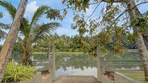 A concrete bridge over a calm lake with surrounding greenery and trees. - Deluxe Thiruvallam Lakeview (Thiruvananthapuram)
