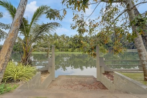 Un puente de concreto sobre un lago tranquilo, rodeado de vegetación y árboles.