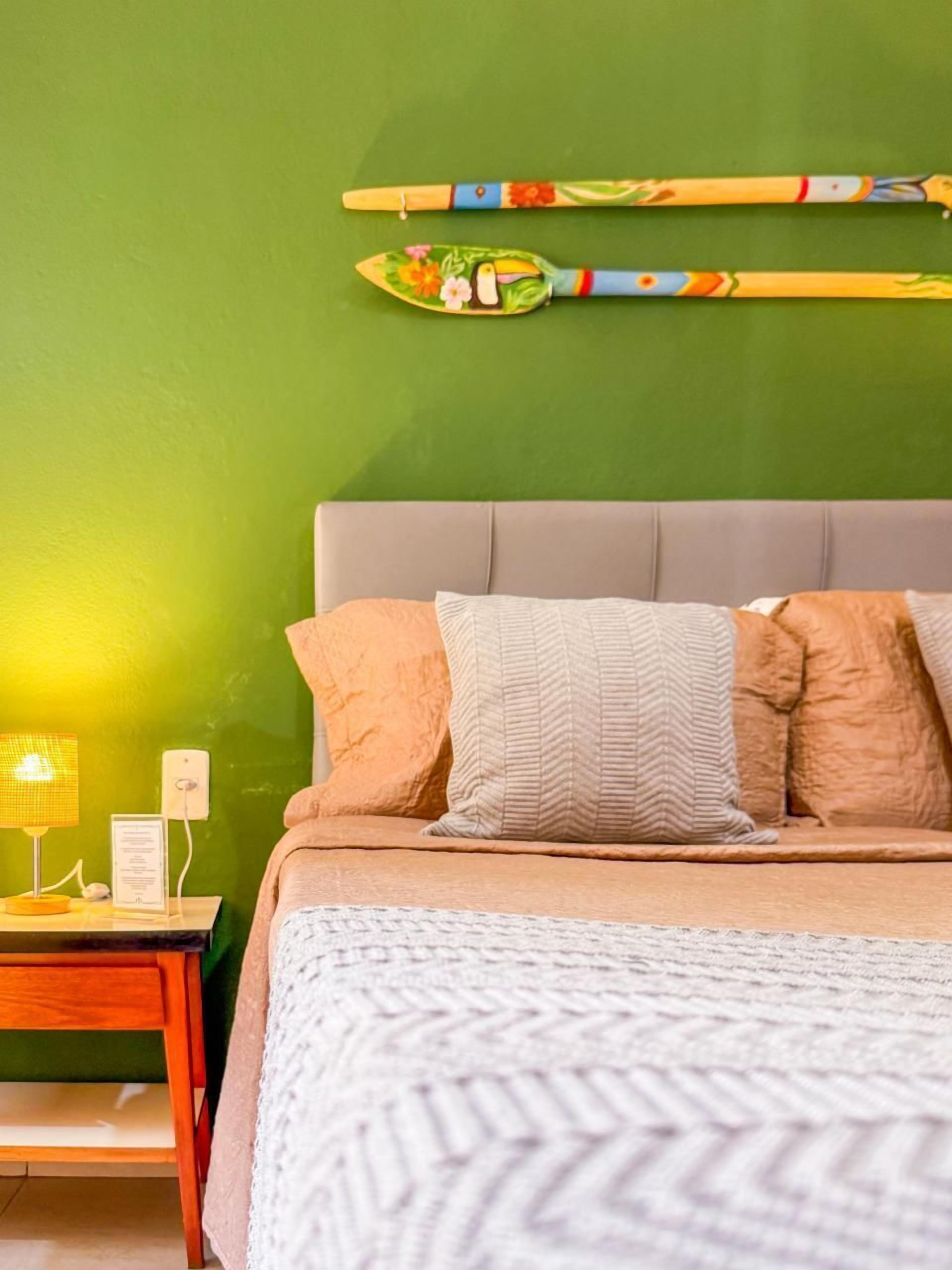 Cama com manta branca texturizada, cabeceira cinza e duas almofadas.