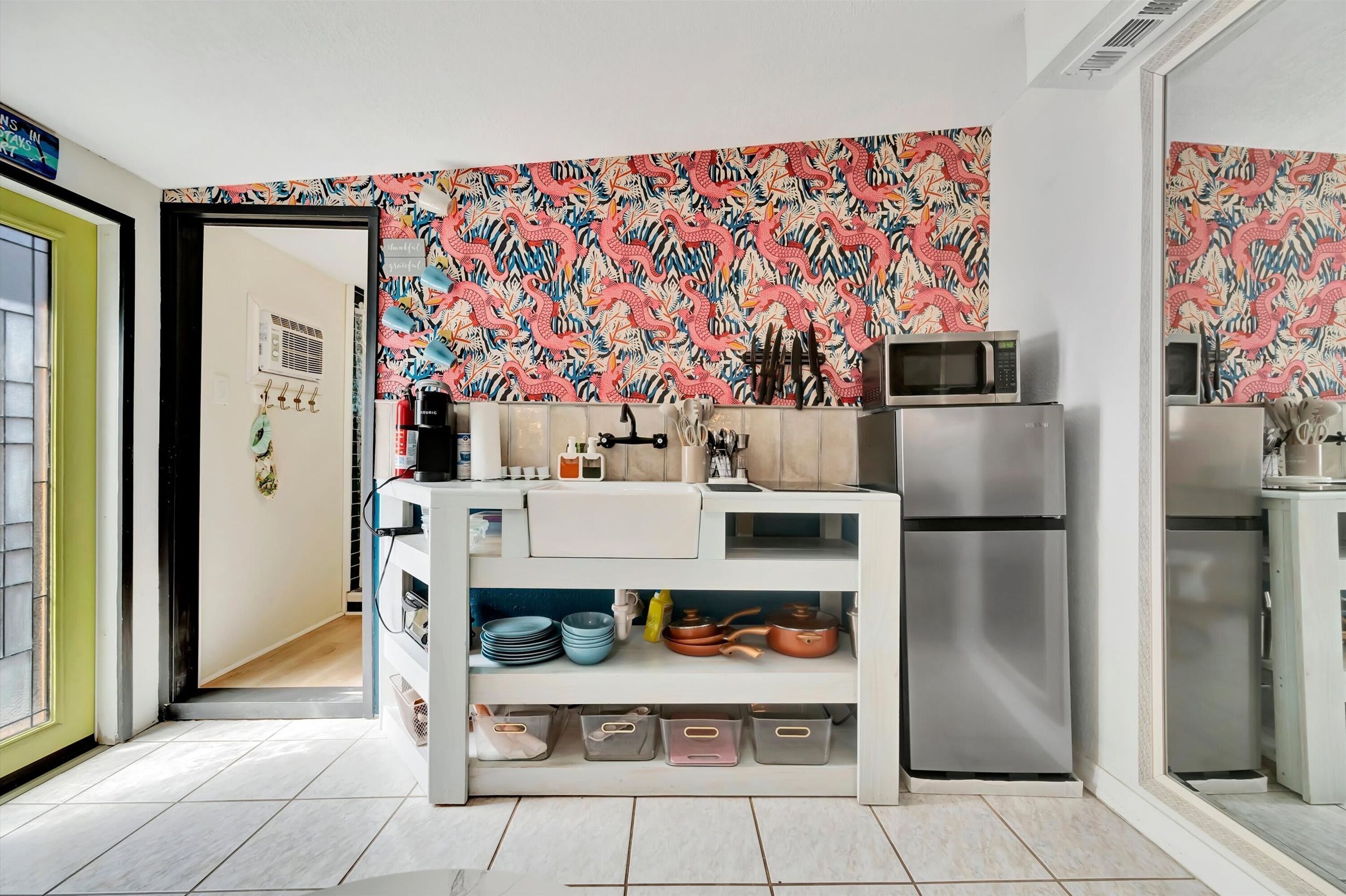 A kitchen with a microwave, refrigerator, and storage shelves.