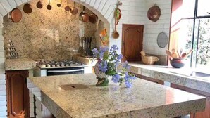 A kitchen with a granite countertop, white brick backsplash, and a hanging pot rack. - w Charming 4BR Getaway w Pool BBQ Clay Oven (Chaclacayo)