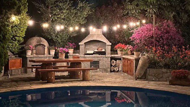 A pool with a stone barbecue area, surrounded by potted plants and flowers. - w Charming 4BR Getaway w Pool BBQ Clay Oven (Chaclacayo)