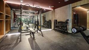 Ein Fitnessraum mit Squat-Stange, Bänken und verschiedenen Gewichten.