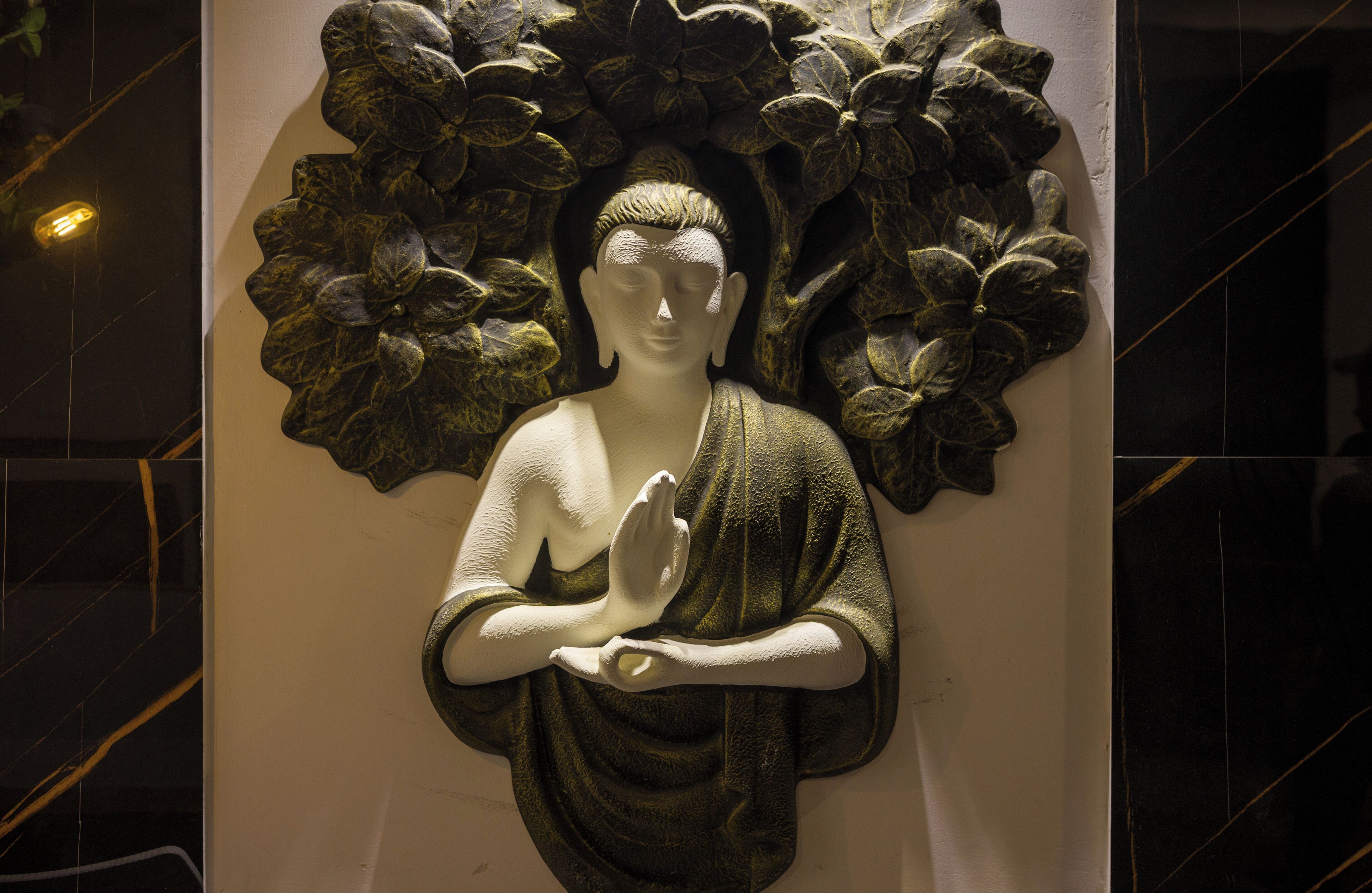 Estatua de una figura vestida con atuendo tradicional, rodeada de un diseño floral.