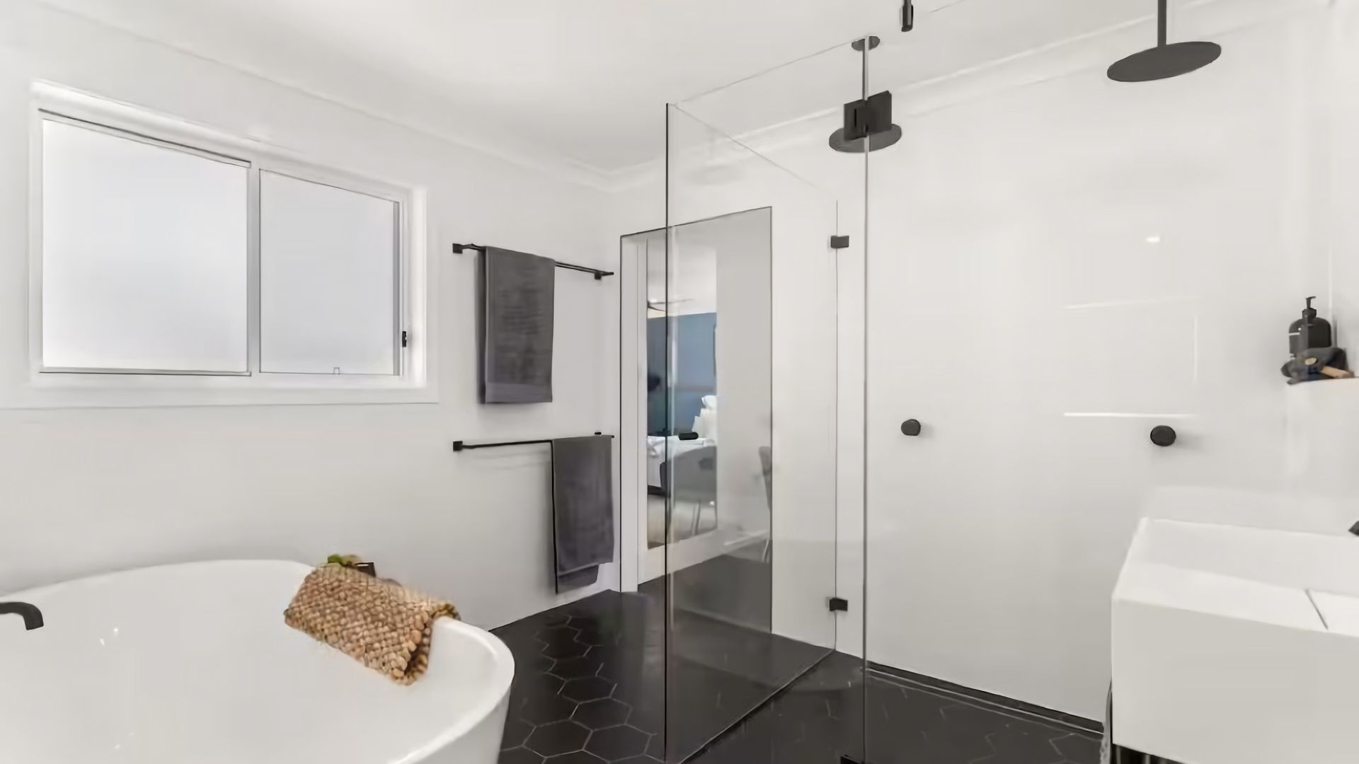 Un baño moderno con cabina de ducha de vidrio, un lavabo blanco y un espejo grande.